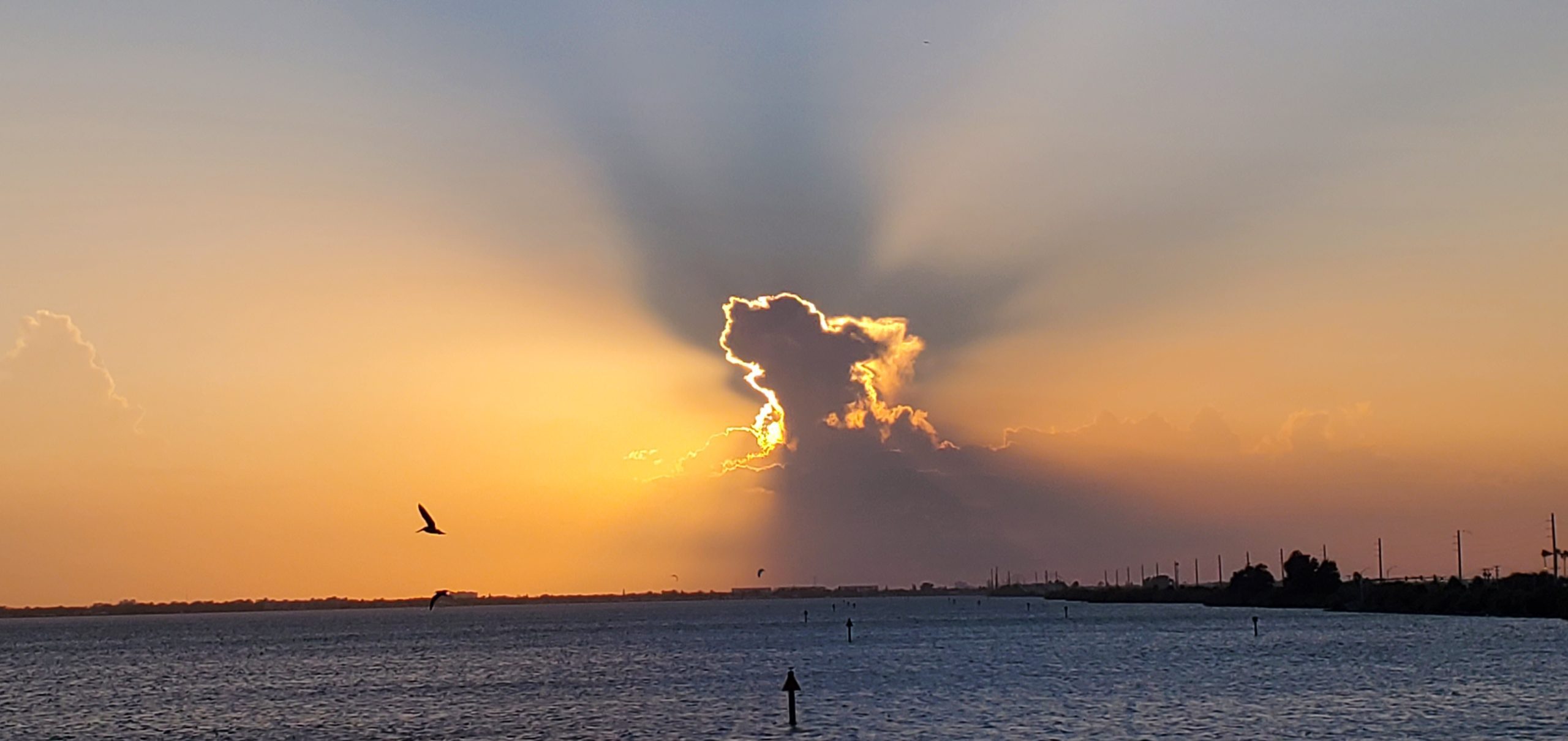 Sunbeams spreading from behind a cloud over the Banana River at sunset