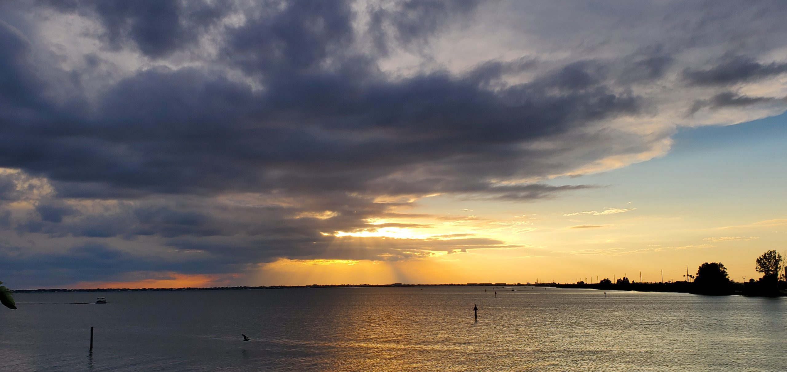 Dramatic cloudy sunset over the water with a small boat on the horizon