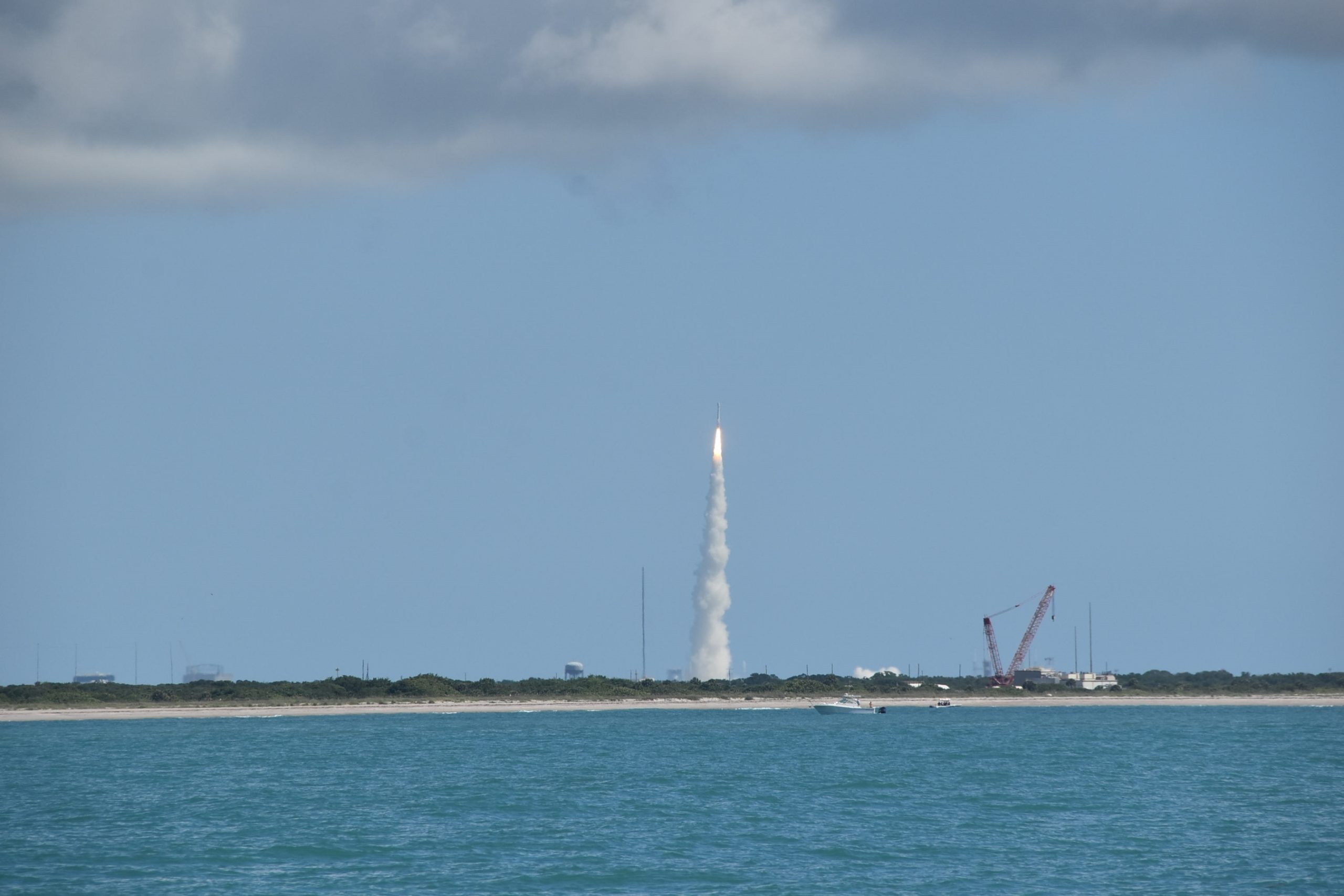 Rocket lifting off from Cape Canaveral with a bright exhaust plume, seen from the water