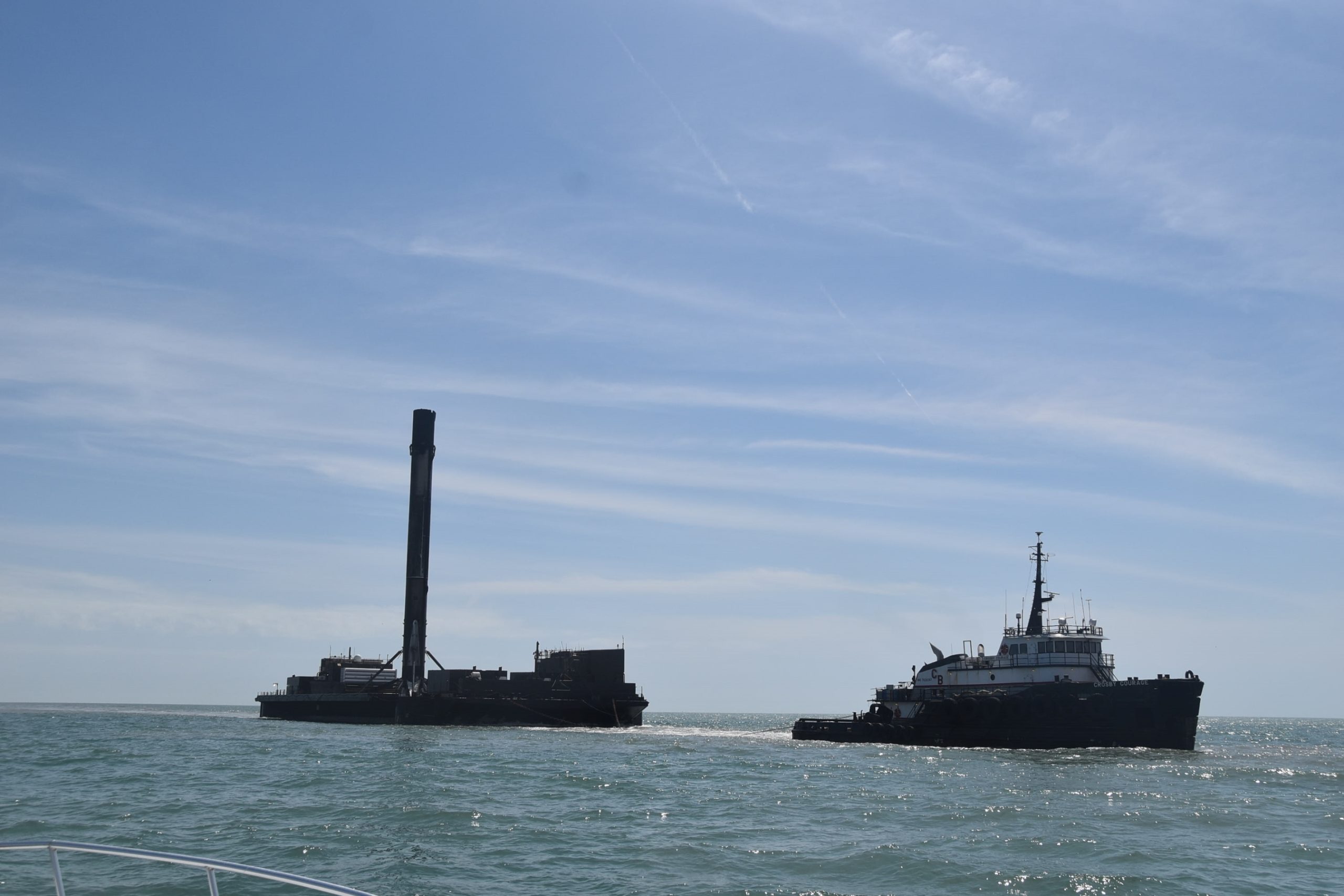 SpaceX Falcon 9 booster standing upright on its recovery barge as it returns to Port Canaveral